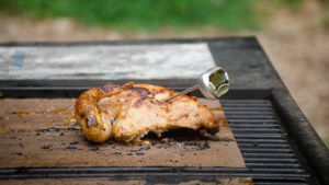 Grilled chicken half with a themometer on a grill