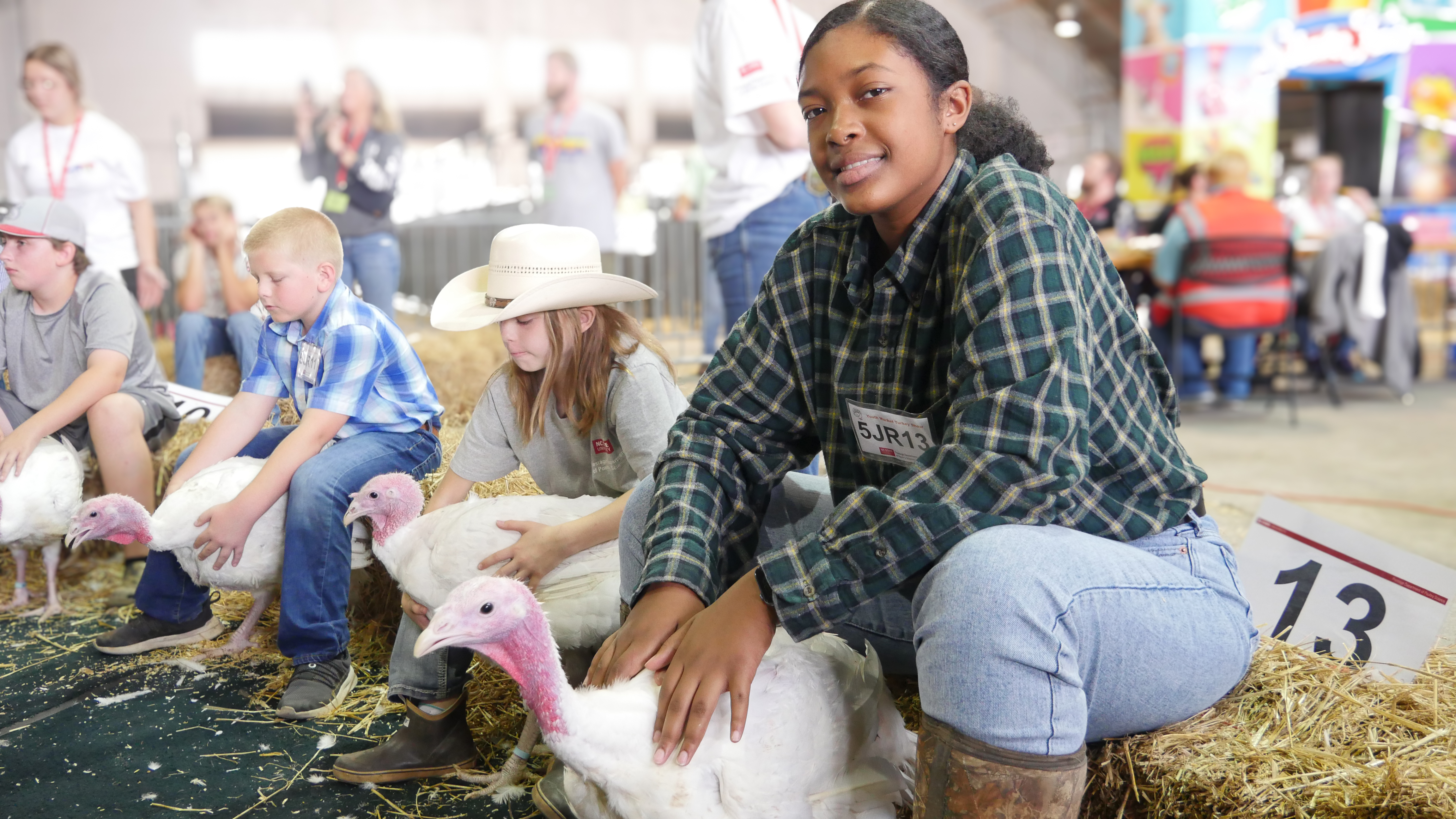 Children pose together with white turkeys.